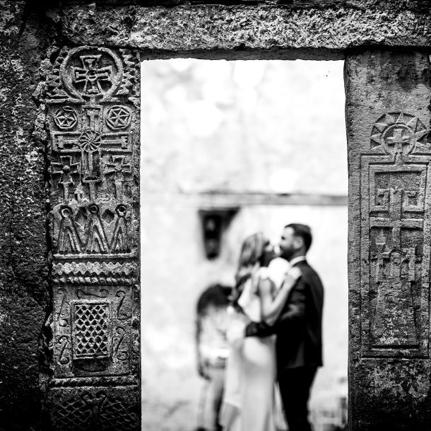 Black and white photo with blurred bride and groom, sharp focus on castle wall